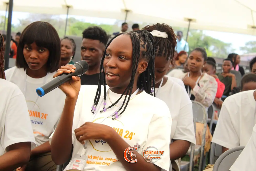 A young delegate speaking into a microphone from her seat