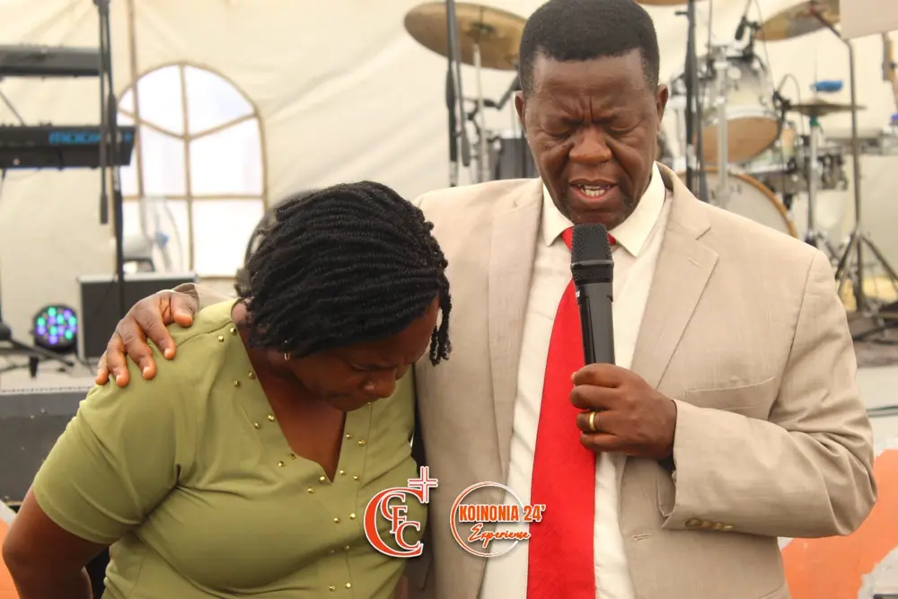 A leader praying with his arm around a woman