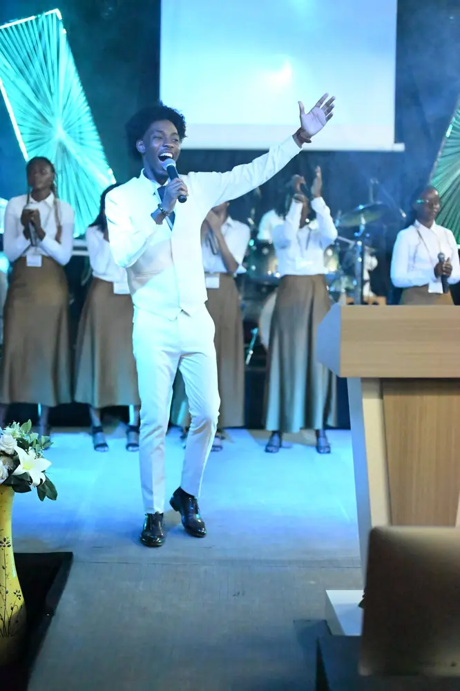 A worship leader with arms raised on stage