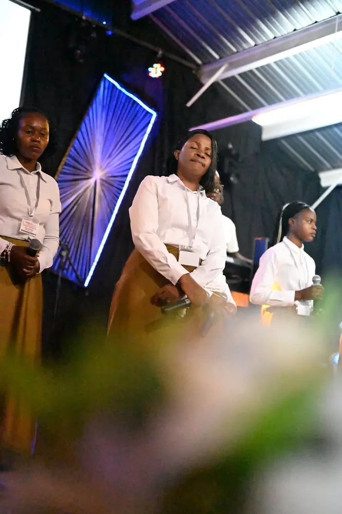 Singers leading worship, seen past the stage flowers